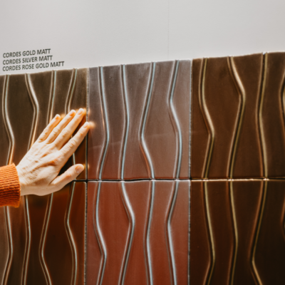 Persona admirando el color y textura de los azulejos metalizados INTHETILE